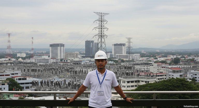 Philippine transmission towers and grid at dusk with city skyline in the background